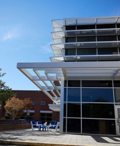 Modern ECSU campus building with glass walls and white architectural features on a sunny day.
